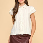 Woman wearing a white blouse with ruffled sleeves and a brown leather skirt on a beige background