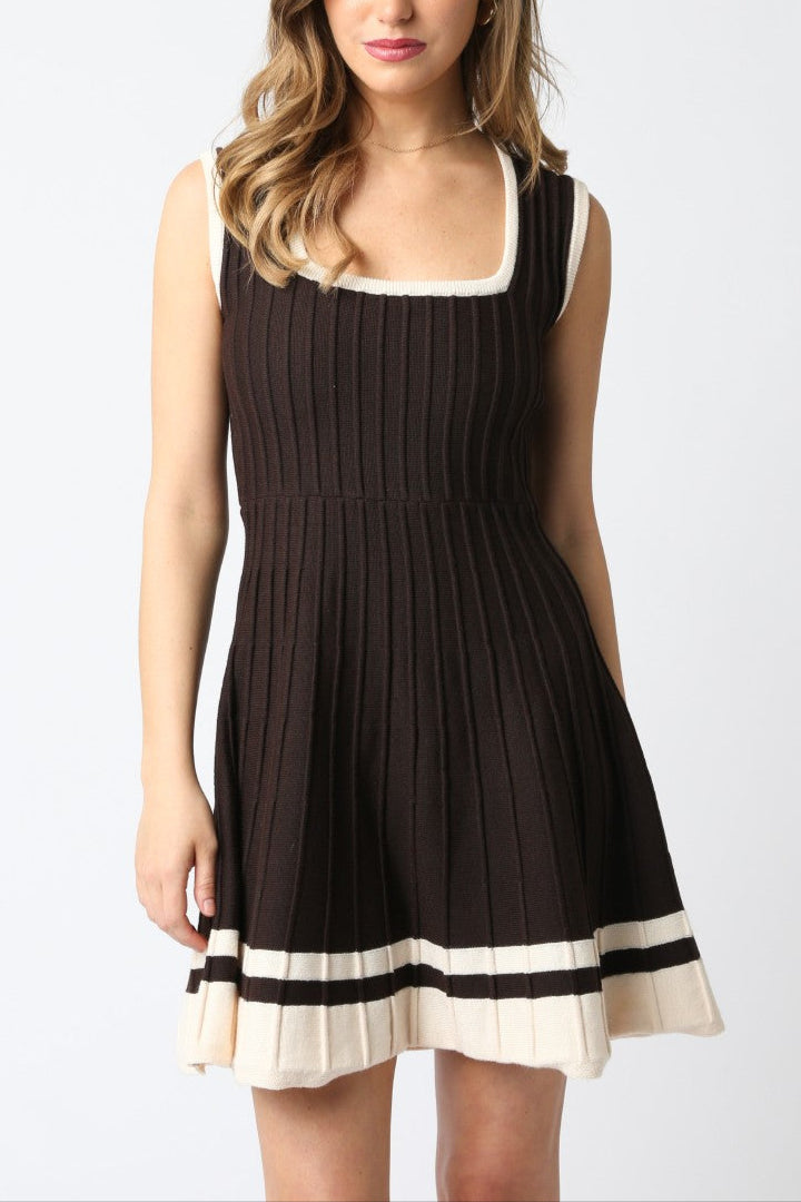 Woman wearing a black dress with white trim on a plain background