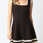 Woman wearing a black dress with white trim on a plain background