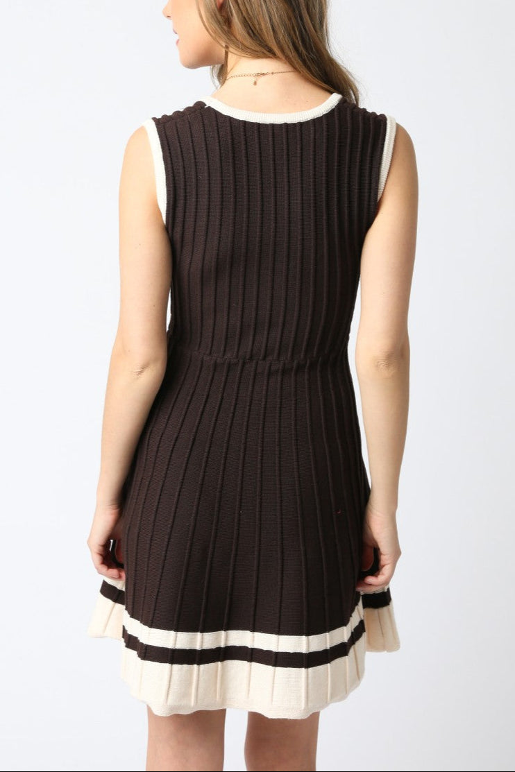 Woman wearing a black sleeveless dress with a white trim on a white background
