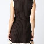 Woman wearing a black sleeveless dress with a white trim on a white background