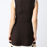 Woman wearing a black sleeveless dress with a white trim on a white background