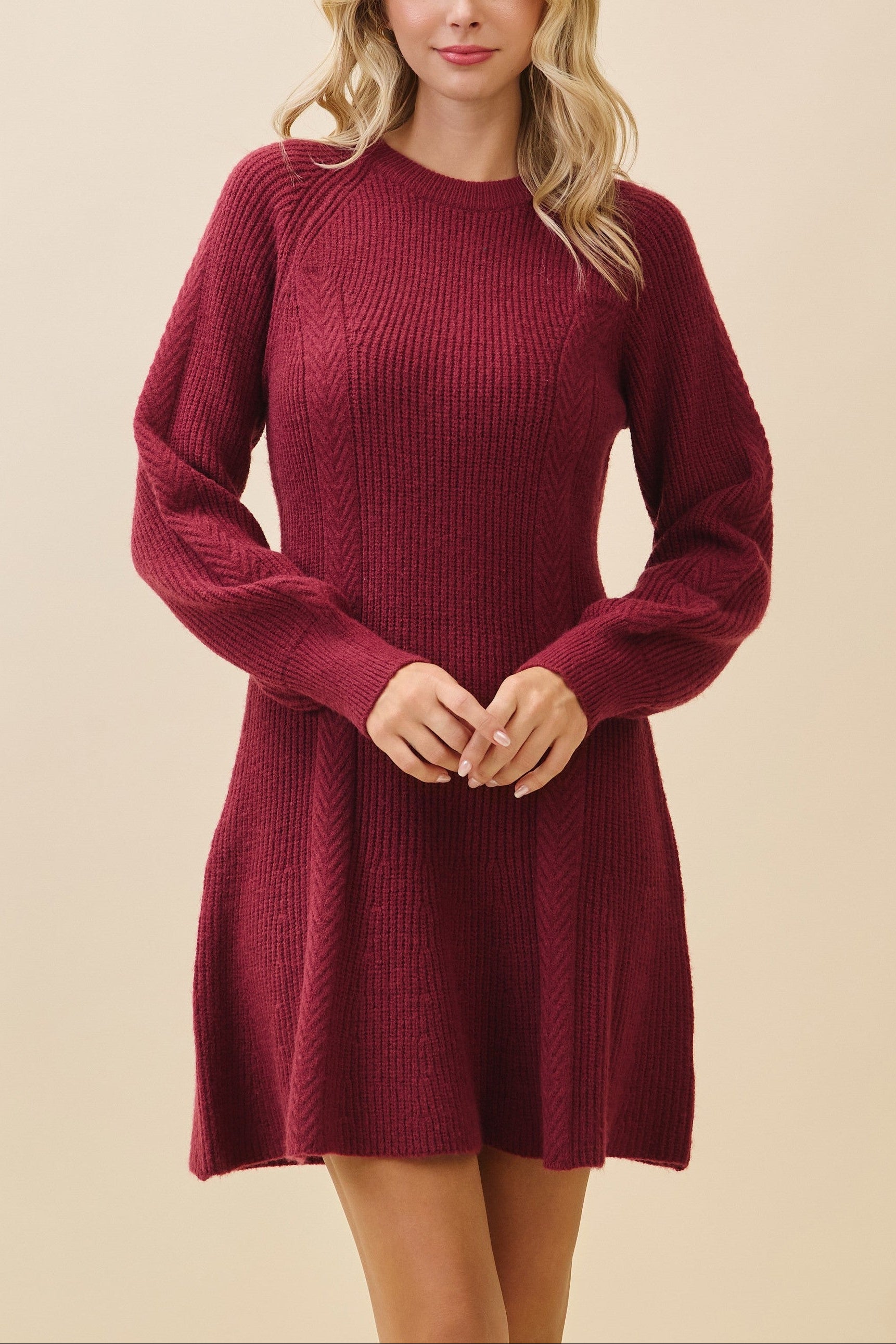 Woman wearing a burgundy knit dress against a beige background