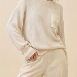Woman wearing a beige sweater and pants against a beige background