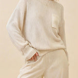 Woman wearing a beige sweater and pants against a beige background