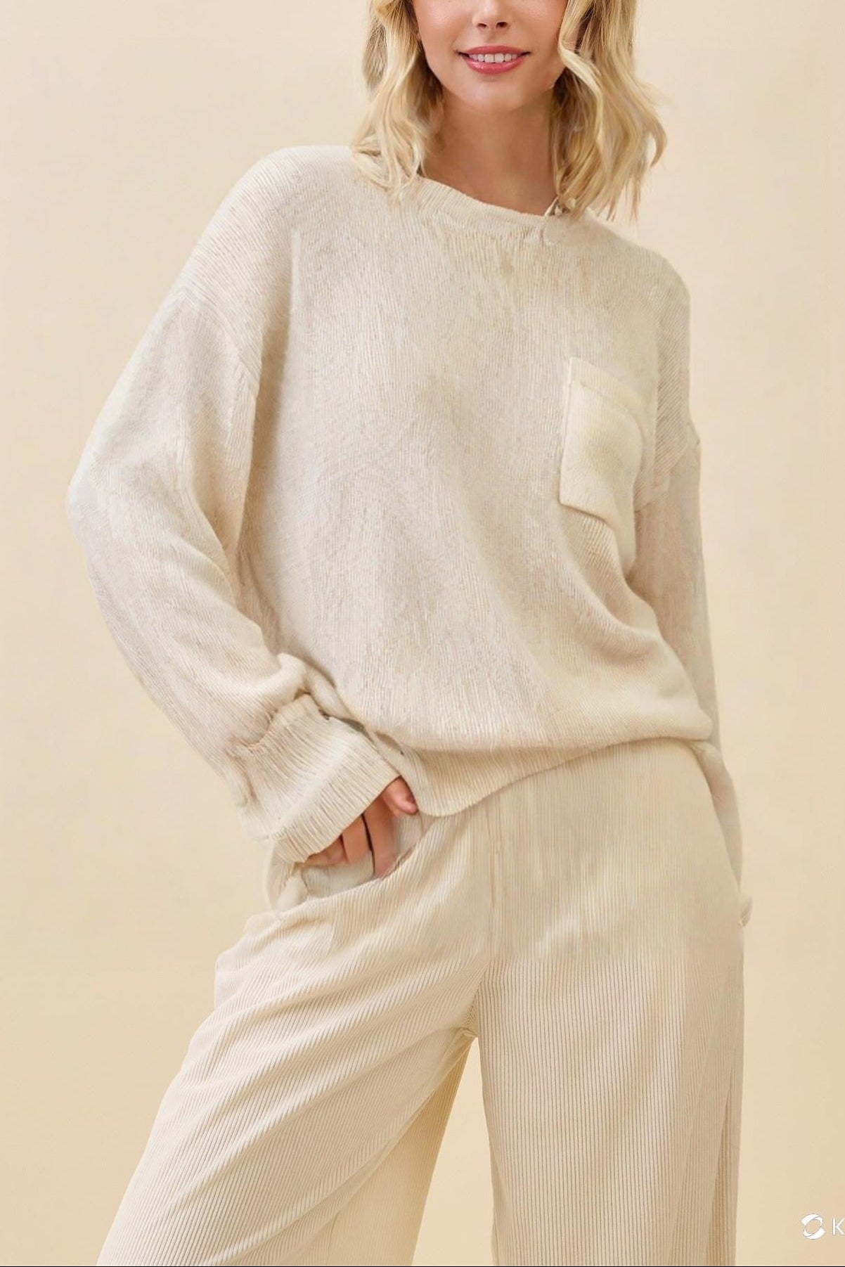 Woman wearing a beige sweater and pants against a beige background
