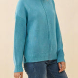 Woman wearing a blue sweater against a beige background