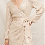 Woman wearing a sparkly gold dress against a neutral background