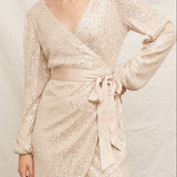 Woman wearing a sparkly gold dress against a neutral background