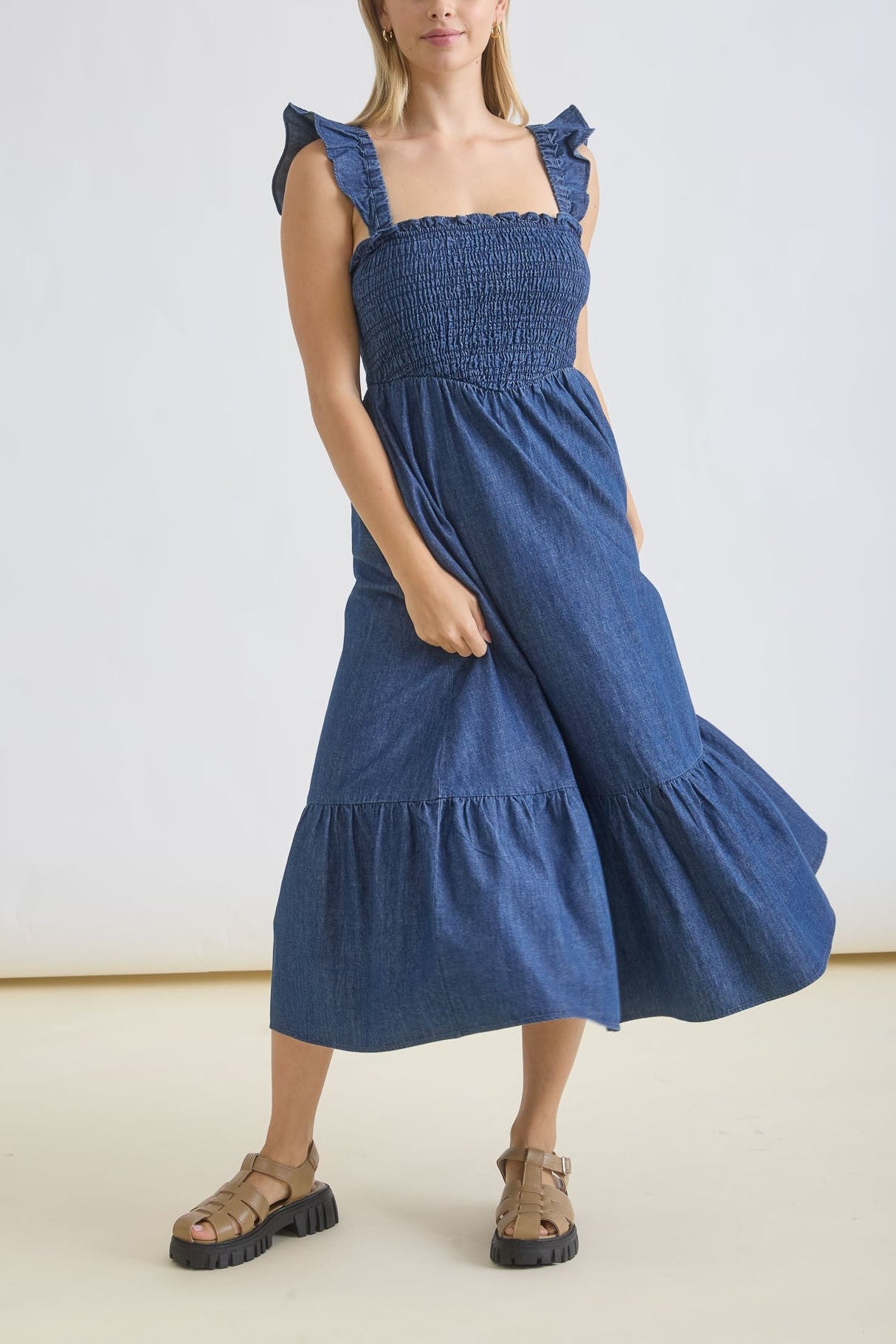 Woman wearing a blue dress standing against a white background