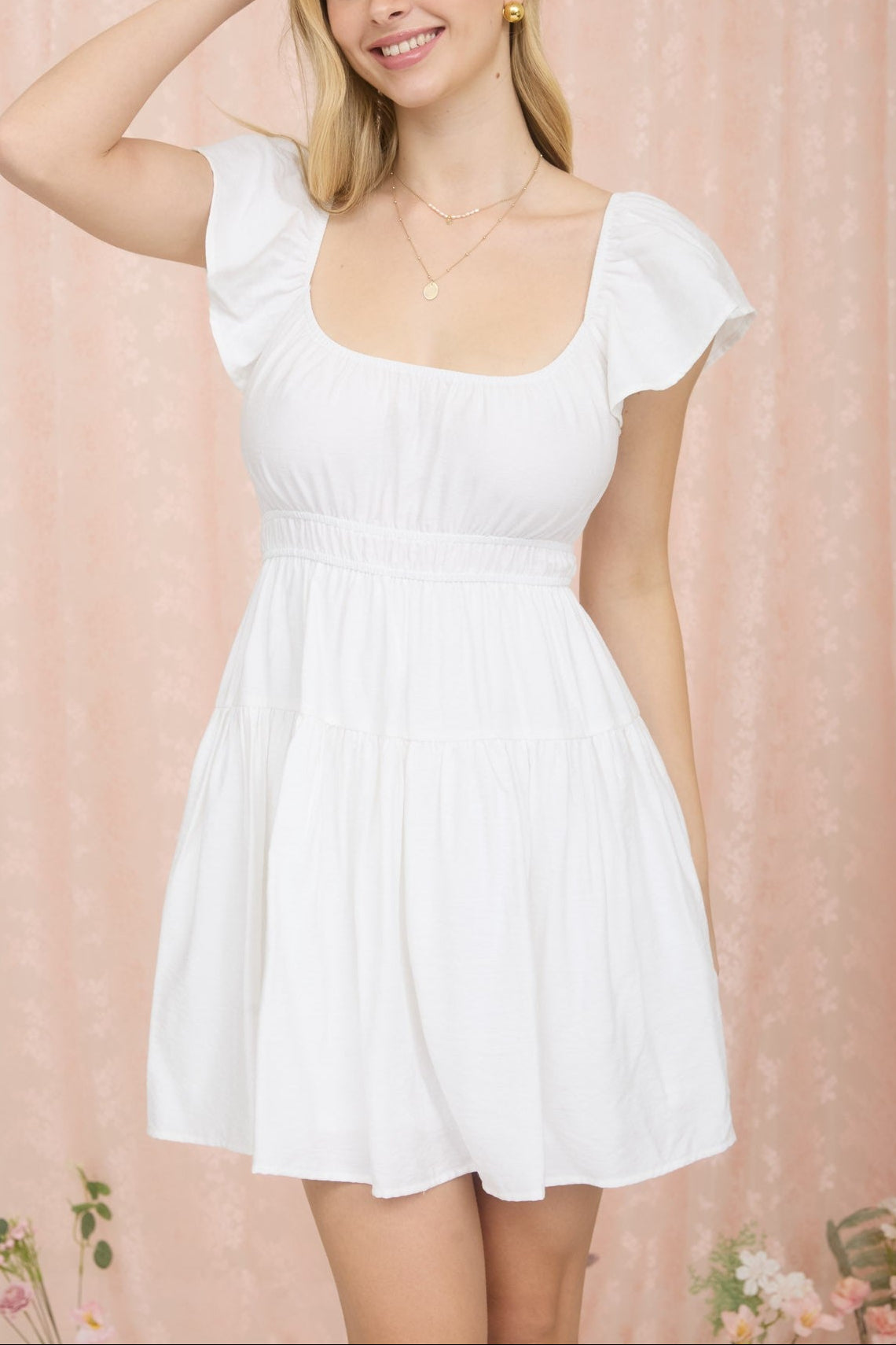 Woman wearing a white dress against a pink floral background