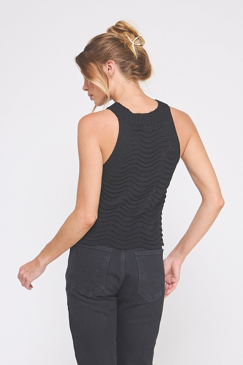 Woman wearing a black sleeveless top and pants on a white background