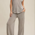 Person wearing a gray outfit with wide-leg pants on a beige background