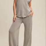 Person wearing a gray outfit with wide-leg pants on a beige background