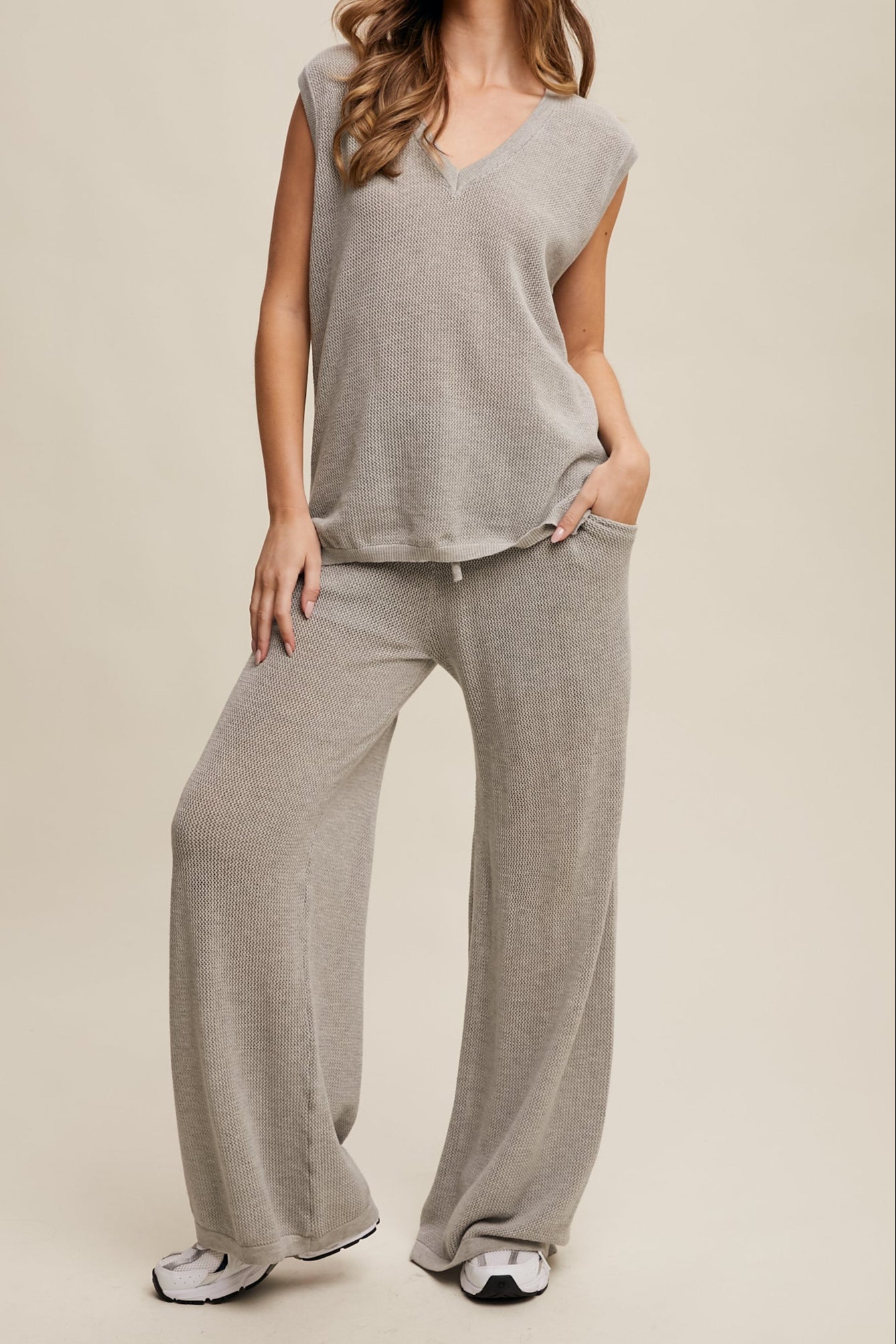 Person wearing a gray outfit with wide-leg pants on a beige background
