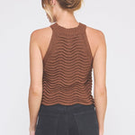 Woman wearing a brown sleeveless knitted top against a white background