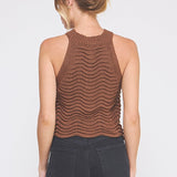 Woman wearing a brown sleeveless knitted top against a white background