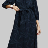 Woman wearing a navy dress with a subtle pattern on a red background