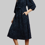 Woman wearing a navy dress against a red background