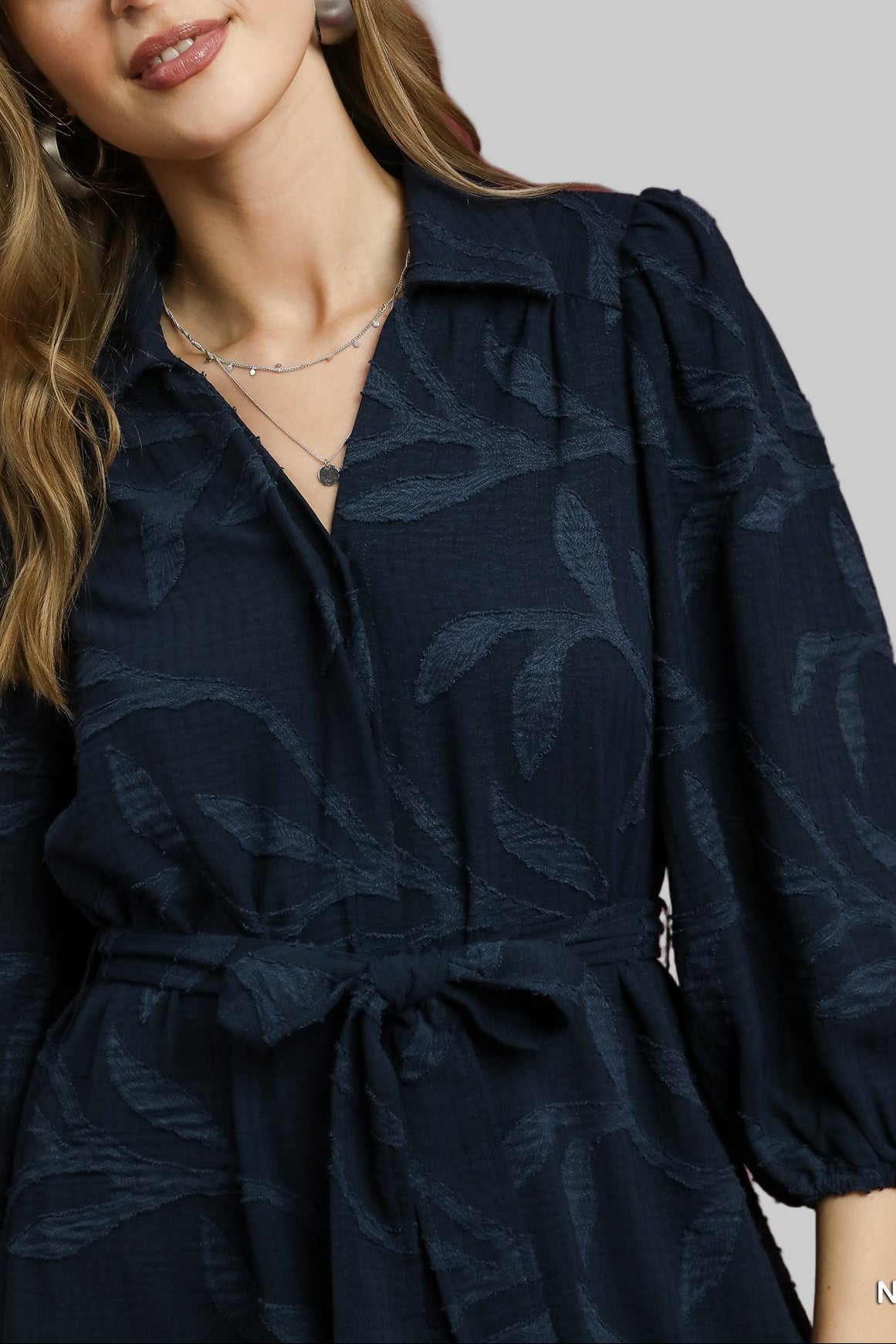 Woman wearing a navy blue dress with leaf pattern against a red background