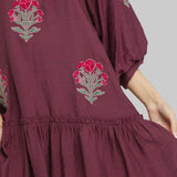 Maroon dress with floral embroidery on a plain background