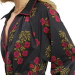 Woman wearing a black floral dress with a plain background