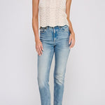 Woman wearing a white sleeveless top and blue jeans on a light gray background
