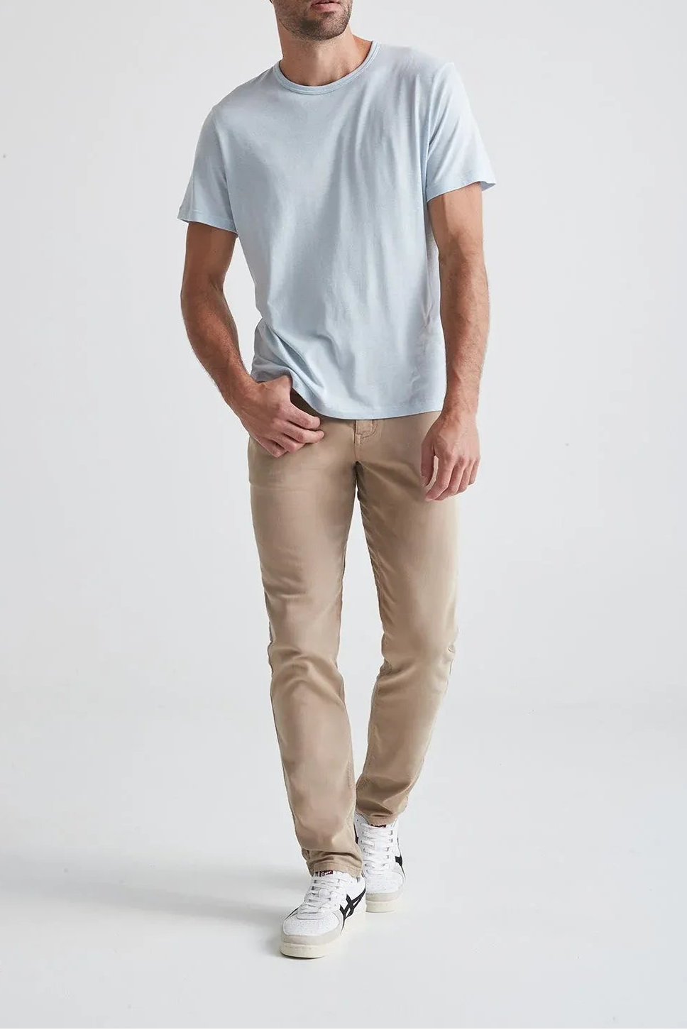 Man wearing a light blue t-shirt and beige pants on a white background