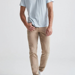 Man wearing a light blue t-shirt and beige pants on a white background