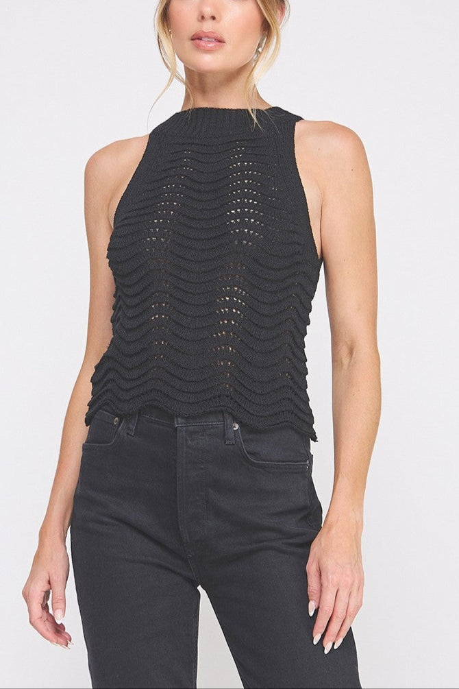 Woman wearing a black sleeveless top with a textured design on a white background