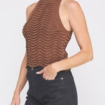 Woman wearing a brown sleeveless knit top against a white background