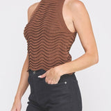 Woman wearing a brown sleeveless knit top against a white background