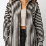 Woman wearing a black and white striped shirt over a beige top and black pants on a white background