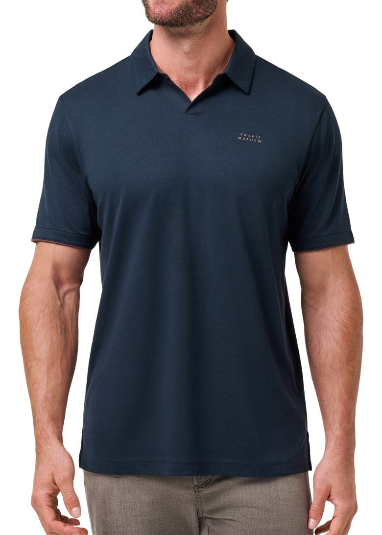 Man wearing a navy blue polo shirt with a logo on a white background