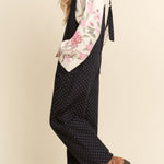 Woman wearing a floral apron over a polka dot dress on a beige background
