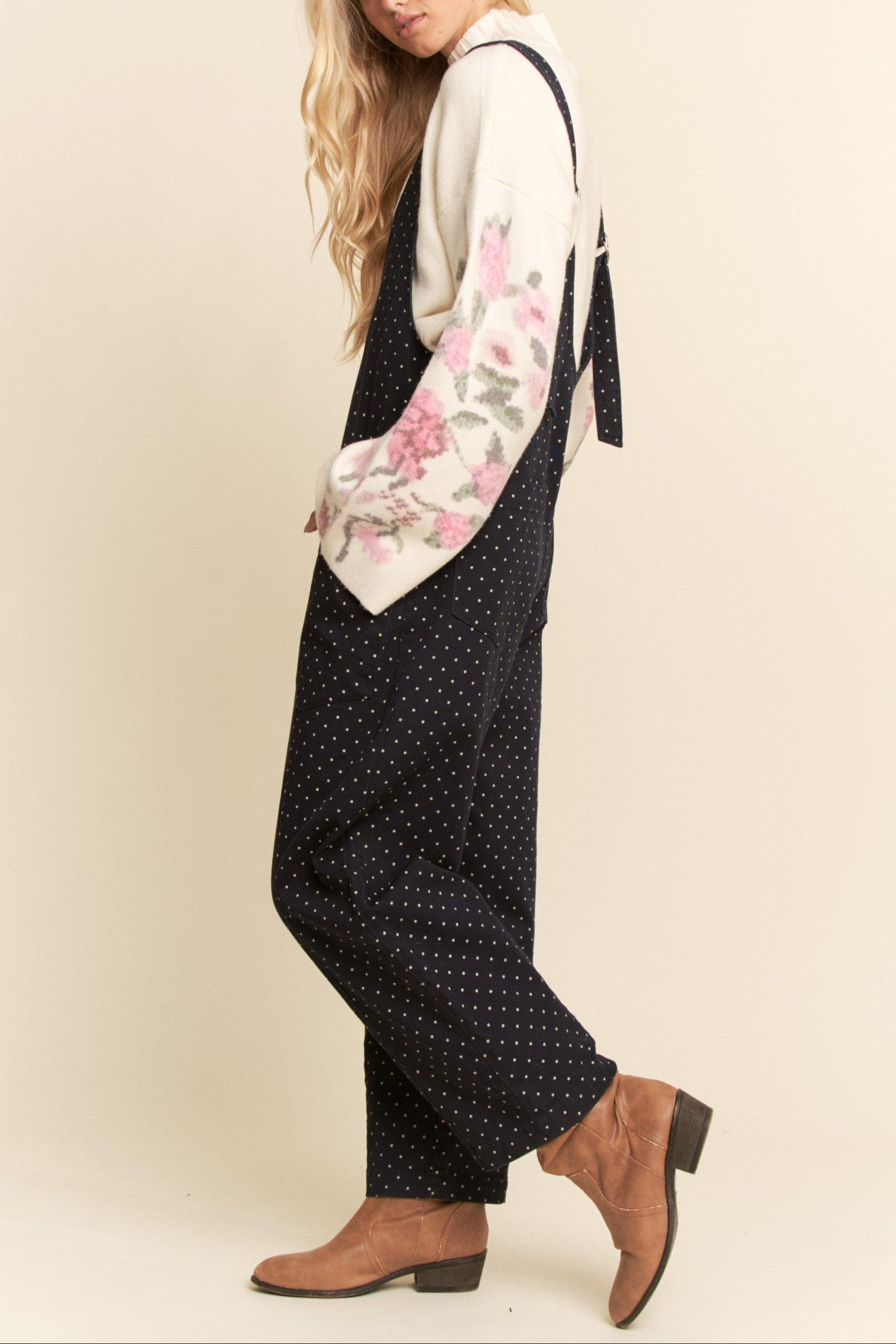 Woman wearing a floral apron over a polka dot dress on a beige background