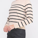 Woman wearing a beige sweater with black stripes on a white background