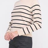 Woman wearing a beige sweater with black stripes on a white background