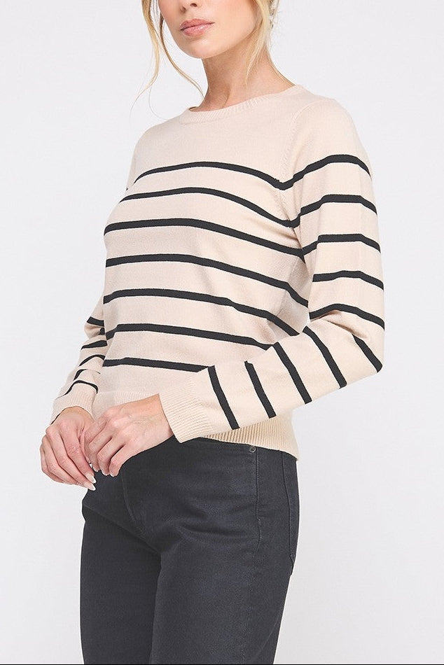 Woman wearing a beige sweater with black stripes on a white background