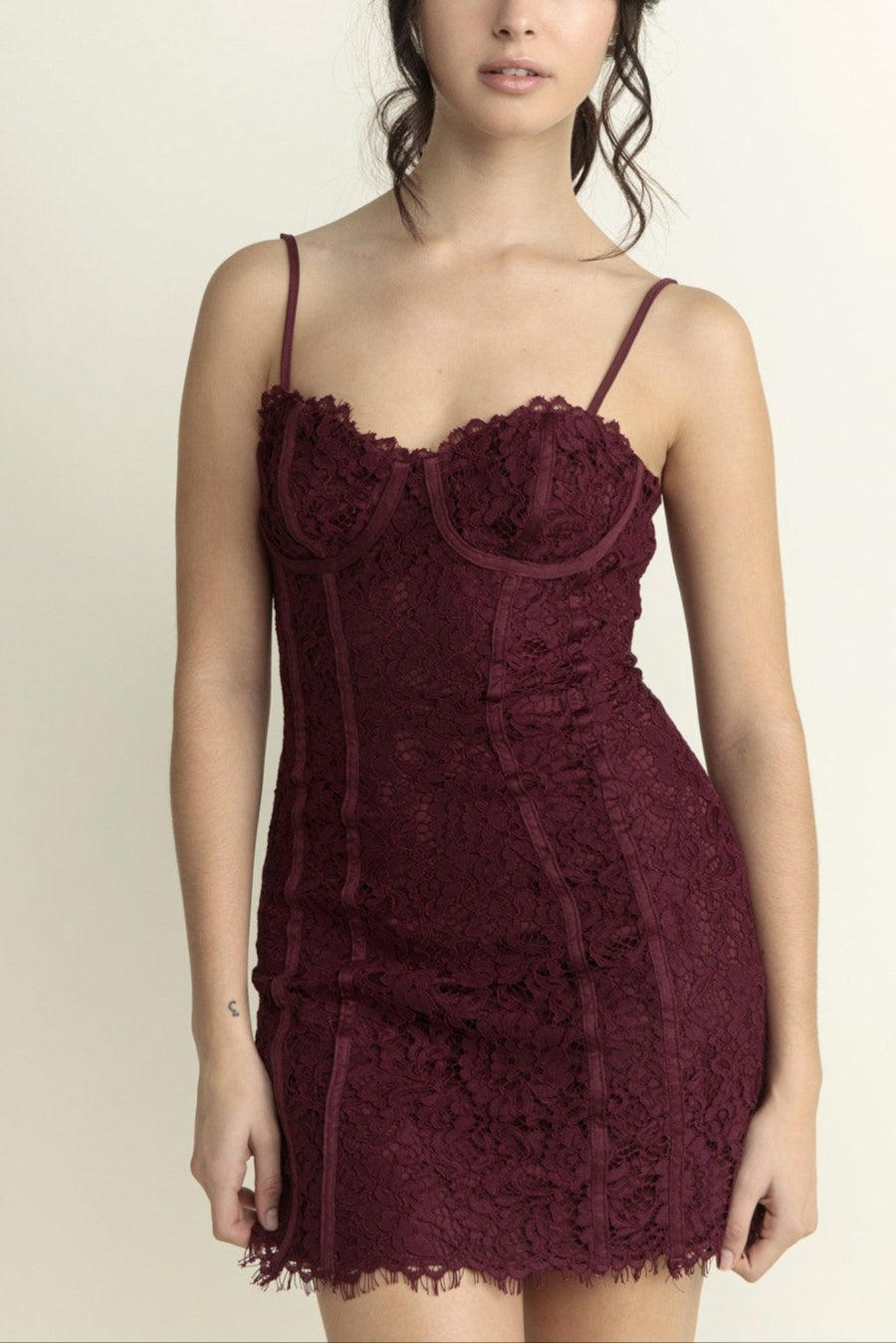 Woman wearing a burgundy lace dress against a plain background