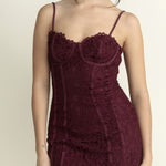 Woman wearing a burgundy lace dress against a plain background