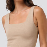 Woman wearing a beige tank top against a plain background