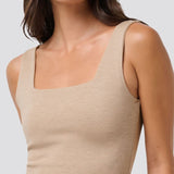 Woman wearing a beige tank top against a plain background
