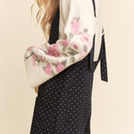 Woman wearing a floral blouse and black polka dot dress on a beige background