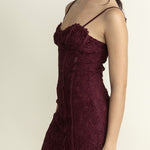 Woman wearing a burgundy lace dress against a plain background