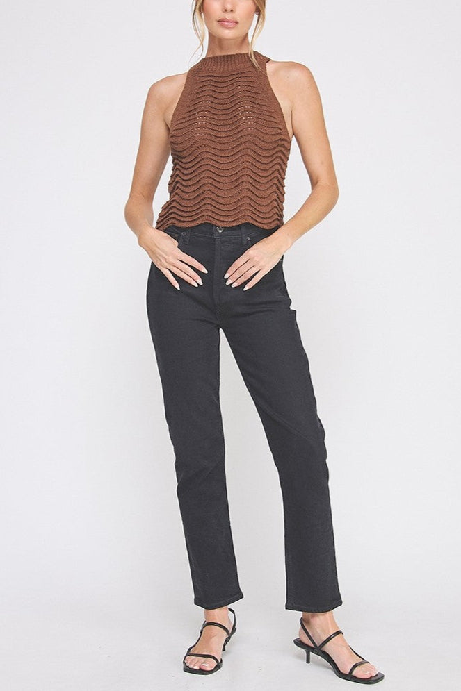 Woman wearing a brown ribbed top and black pants on a white background