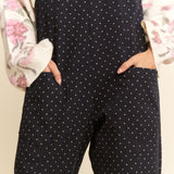 Black polka dot jumpsuit worn by a person with a floral-patterned garment in the background.
