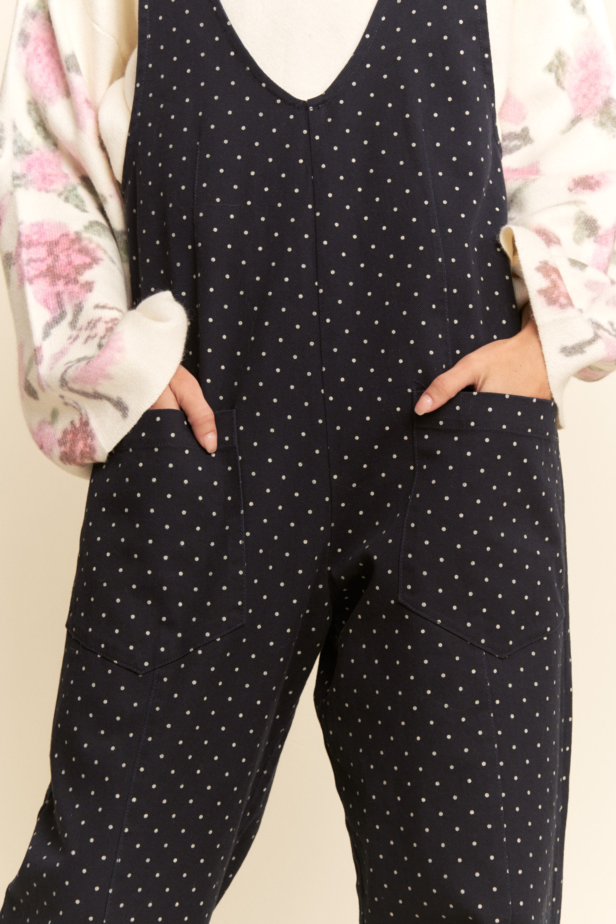 Black polka dot jumpsuit worn by a person with a floral-patterned garment in the background.
