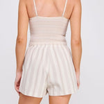Woman wearing a beige romper with thin straps on a white background