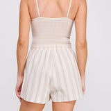 Woman wearing a beige romper with thin straps on a white background